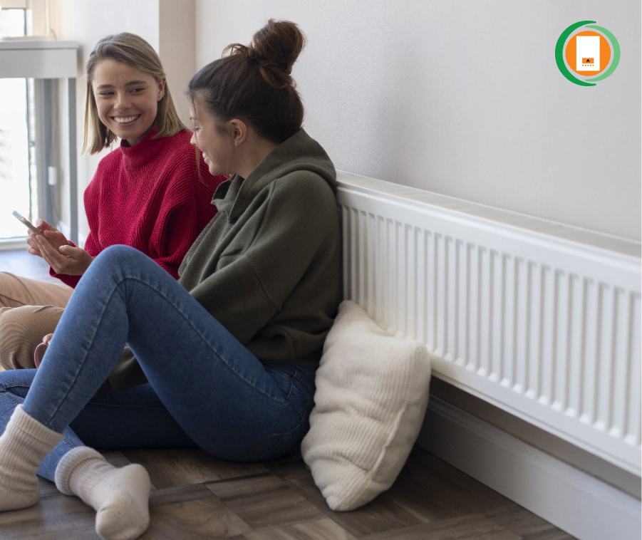 Two smiling girls relaxing on couch in a warm home with new ECO4 heating system